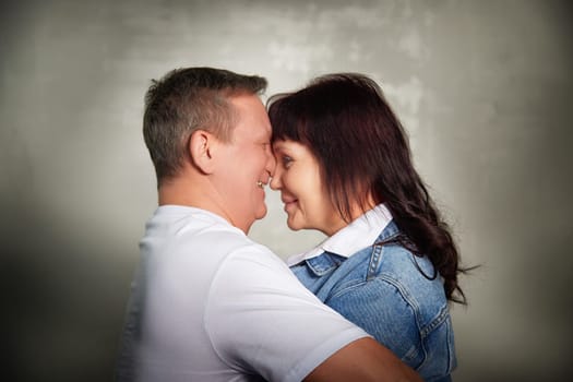 A middle-aged couple shares a joyful moment, embracing and smiling at each other inside their apartment, showcasing their love and connection.