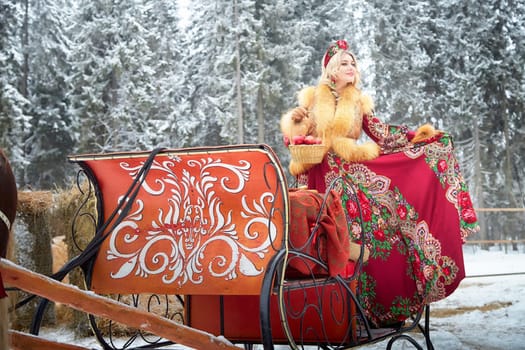 A girl in traditional Russian dress interacts with a horse during the winter Maslenitsa celebration.