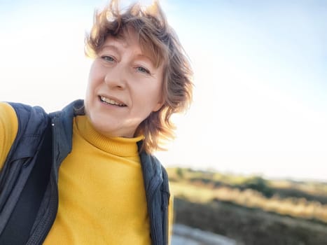 A woman enjoying a sunny day takes a selfie while exploring the outdoors, capturing her travel adventure and excitement.