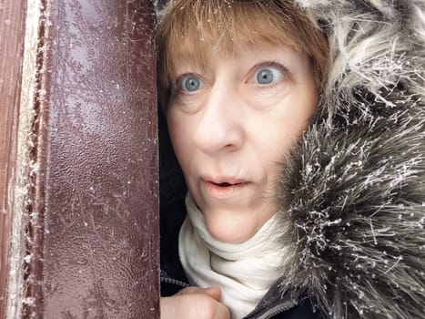 Blonde woman in a cozy winter parka enjoying a chilly excursion while capturing a selfie in a frosty environment