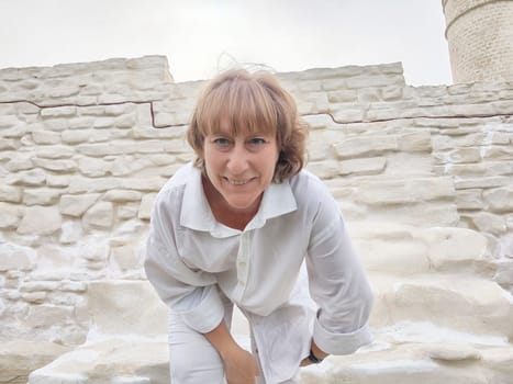 A blonde woman captures a selfie while exploring ancient ruins, showcasing her excitement for travel and adventure as a blogger.