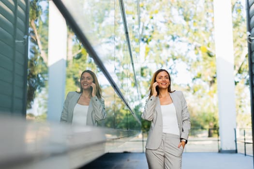 Professional woman walks with ease, smiling as she focuses on her phone, blending modern lifestyle with the tranquility of nature in the background