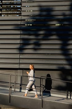 Young business woman strolls through a contemporary outdoor space, exuding confidence while dressed in sleek attire. The warm light accentuates her stylish presence