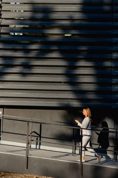 Young business woman strolls through a contemporary outdoor space, exuding confidence while dressed in sleek attire. The warm light accentuates her stylish presence