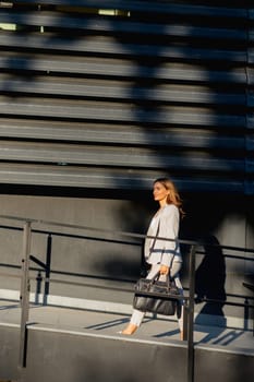 Young business woman strolls through a contemporary outdoor space, exuding confidence while dressed in sleek attire. The warm light accentuates her stylish presence