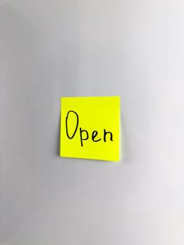 Colored sticky note with the word open. Open written on sticky note on white background. Opening concept, simple design with the word Open, vertical photo