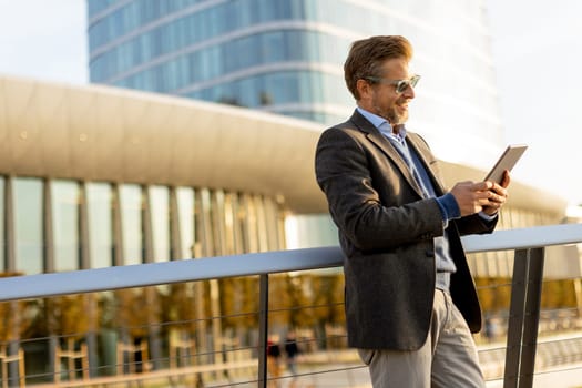 An elegant individual in a blazer stands on a balcony at sunset, holding a tablet and gazing over a vibrant metropolis, embodying professionalism and relaxation.