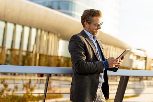 An elegant individual in a blazer stands on a balcony at sunset, holding a tablet and gazing over a vibrant metropolis, embodying professionalism and relaxation.