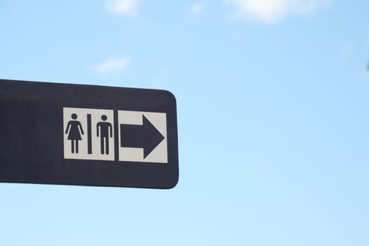 Sign shows restroom symbols with an arrow pointing to the right.