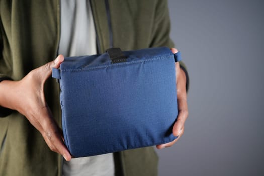 A person holds a compact storage pouch in a casual pose indoors.