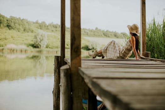 relaxing young woman on wooden pier at the calm lake