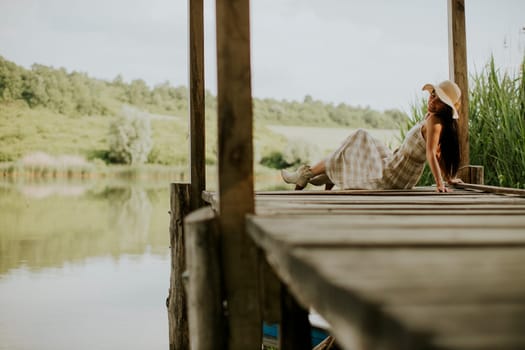 relaxing young woman on wooden pier at the calm lake