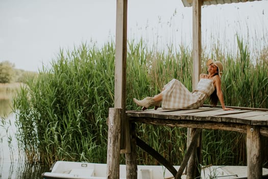 relaxing young woman on wooden pier at the calm lake