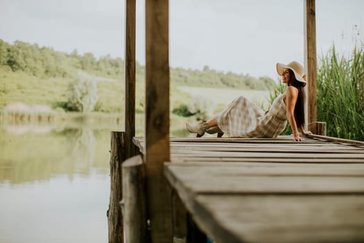 relaxing young woman on wooden pier at the calm lake