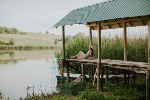 relaxing young woman on wooden pier at the calm lake