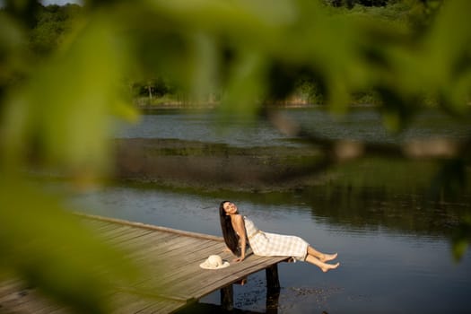 relaxing young woman on wooden pier at the calm lake