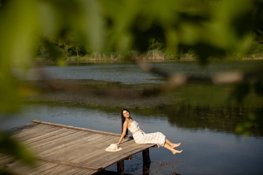 relaxing young woman on wooden pier at the calm lake