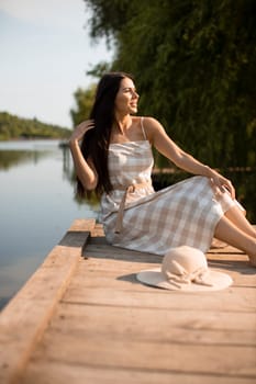 relaxing young woman on wooden pier at the calm lake