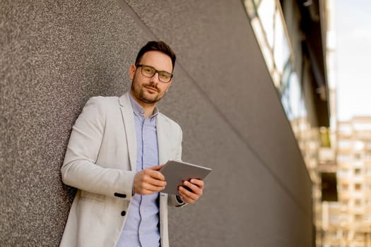Portrait of young businessman with digital tablet standing outdoor