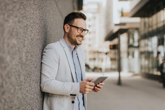 Portrait of a young businessman holding digital tablet outdoor in urban enviroment