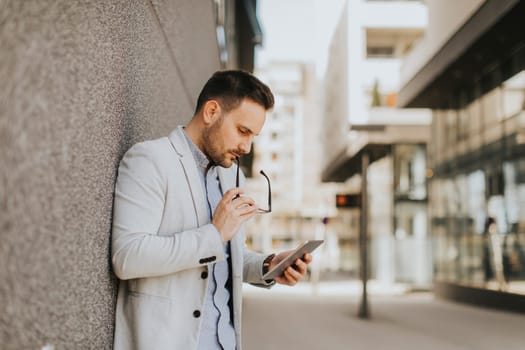 Portrait of a young businessman holding digital tablet outdoor in urban enviroment
