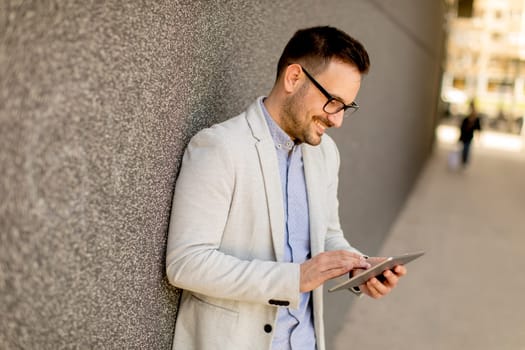 Portrait of a young businessman holding digital tablet outdoor in urban enviroment