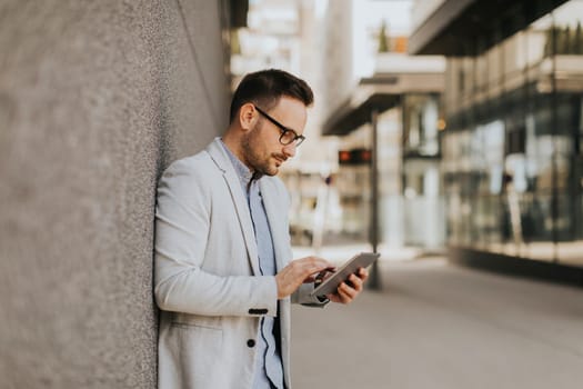 Portrait of a young businessman holding digital tablet outdoor in urban enviroment