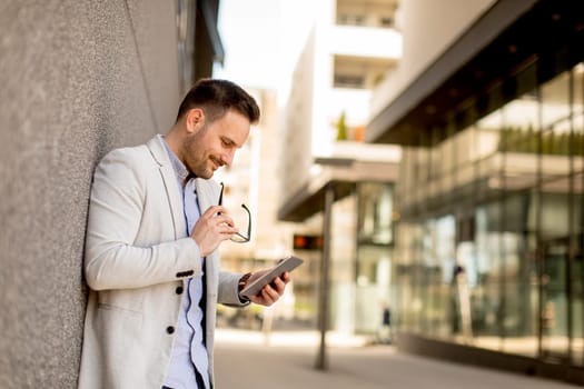 Portrait of a young businessman holding digital tablet outdoor in urban enviroment
