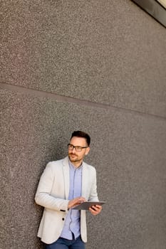 Portrait of a young businessman holding digital tablet outdoor in urban enviroment