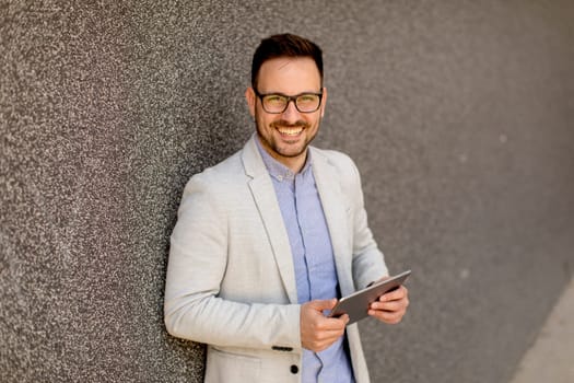 Portrait of a young businessman holding digital tablet outdoor in urban enviroment