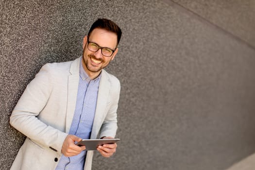 Portrait of a young businessman holding digital tablet outdoor in urban enviroment