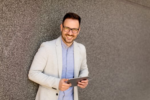 Portrait of a young businessman holding digital tablet outdoor in urban enviroment