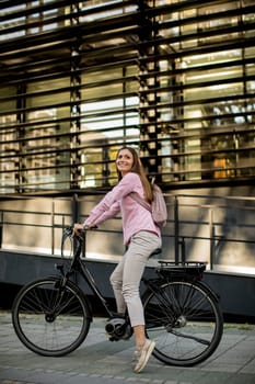Young woman riding e bike in urban enviroment at sunny day
