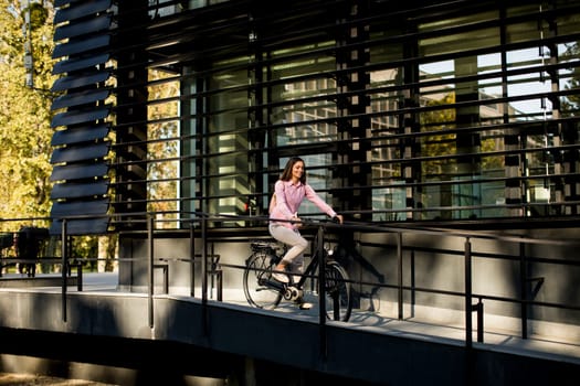 Young woman riding e bike in urban enviroment at sunny day