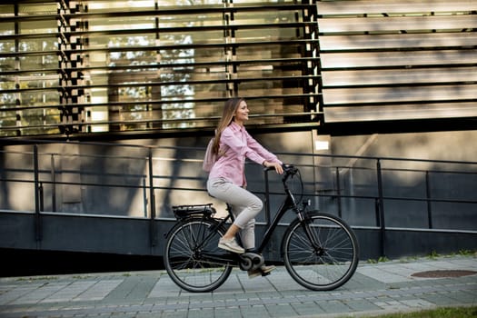 Young woman riding e bike in urban enviroment at sunny day