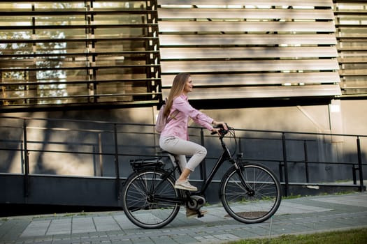 Young woman riding e bike in urban enviroment at sunny day
