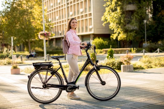 Pretty young woman with modern city electric e-bike clean sustainable urban transportation