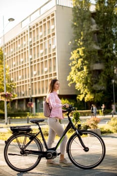 Pretty young woman with modern city electric e-bike clean sustainable urban transportation
