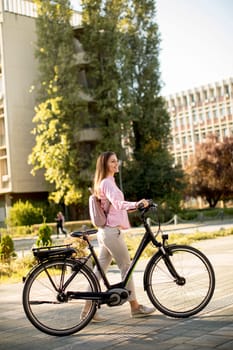 Pretty young woman with modern city electric e-bike clean sustainable urban transportation