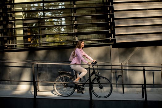 Young woman riding e bike in urban enviroment at sunny day
