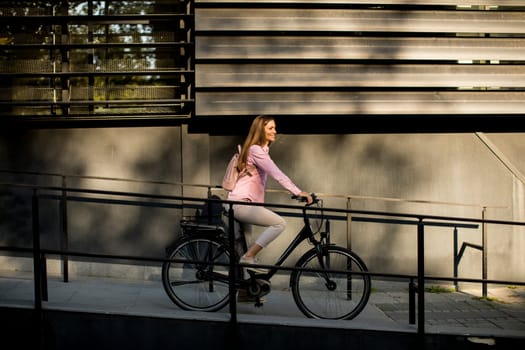 Young woman riding e bike in urban enviroment at sunny day