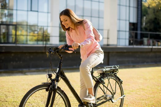 Young woman riding e bike in urban enviroment at sunny day