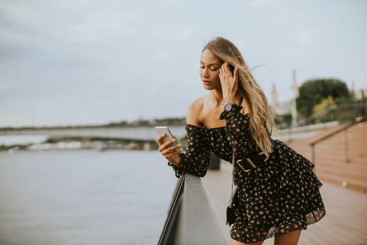 Pretty young long hair brunette woman standing on the riverside