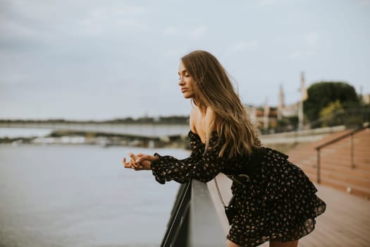 Pretty young long hair brunette woman standing on the riverside