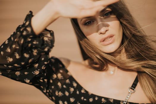 Outdoor portrait of sensual long hair brunette woman covering her face with hand from sunlight