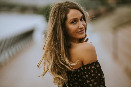 Pretty young long hair brunette woman walking on the riverside