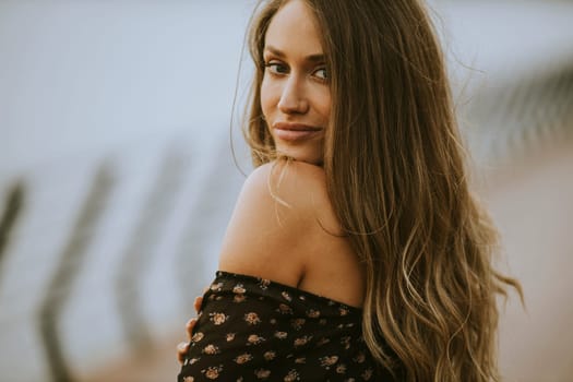 Pretty young long hair brunette woman walking on the riverside