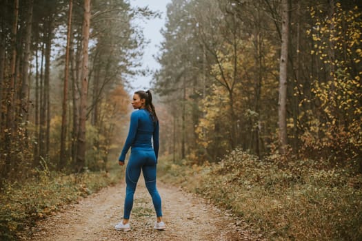 Pretty young woman take a break during outdoor exercise on the forest trail at autumn