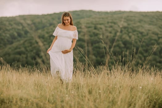 Young pregnant woman relaxing outside in nature at summer day