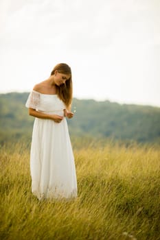Young pregnant woman relaxing outside in nature at summer day